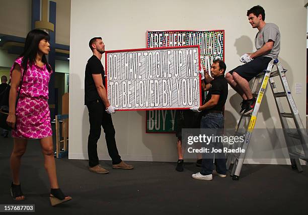 Workers from Safe Art Transport company place a piece of art of the wall of L&M Arts Gallery as Art Basel opens at the Miami Beach Convention Center...