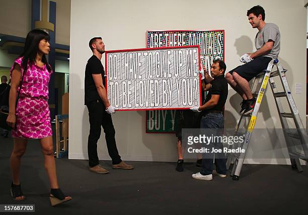 Workers from Safe Art Transport company place a piece of art of the wall of L&M Arts Gallery as Art Basel opens at the Miami Beach Convention Center...