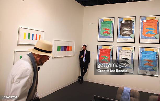 Chris Santa Maria leans against a wall with art hanging on it at the Gemini GEL gallery as Art Basel opens at the Miami Beach Convention Center on...