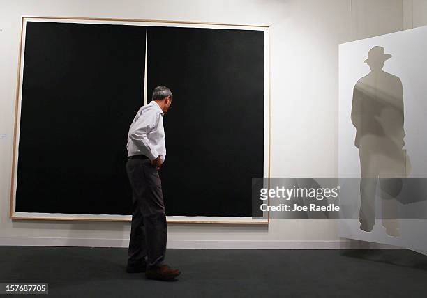An art patron looks at the art on the walls of the Gemini GEL gallery as Art Basel opens at the Miami Beach Convention Center on December 5, 2012 in...