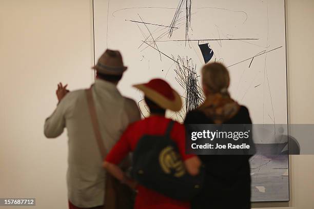 People look at a piece of art in the Galerie Krinzinger as Art Basel opens at the Miami Beach Convention Center on December 5, 2012 in Miami Beach,...