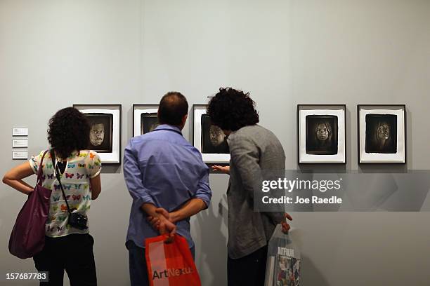 People look at art by Chuck Close in the Two Palms gallery as Art Basel opens at the Miami Beach Convention Center on December 5, 2012 in Miami...