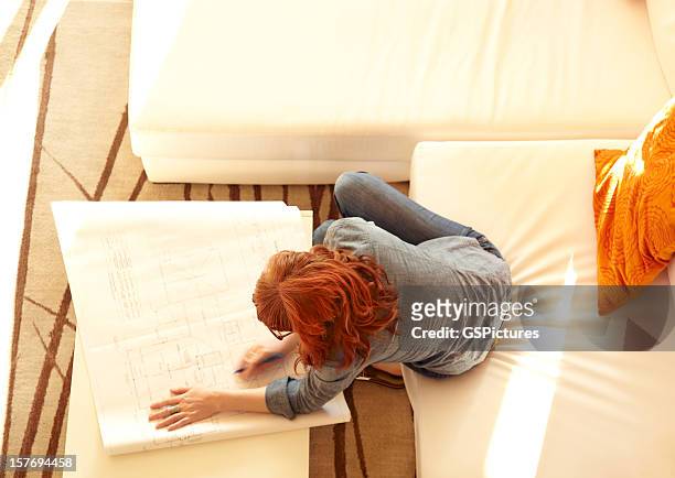 overhead view of woman reviewing architecture plans at home - feng shui house stock pictures, royalty-free photos & images