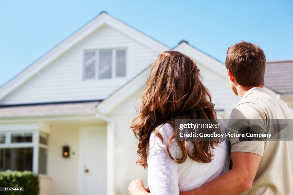 Romantic couple standing in front of their new house