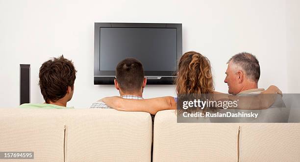 family watching tv. - family watching tv from behind stock pictures, royalty-free photos & images