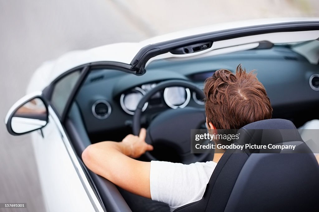 High angle view of young male driving convertible in speed