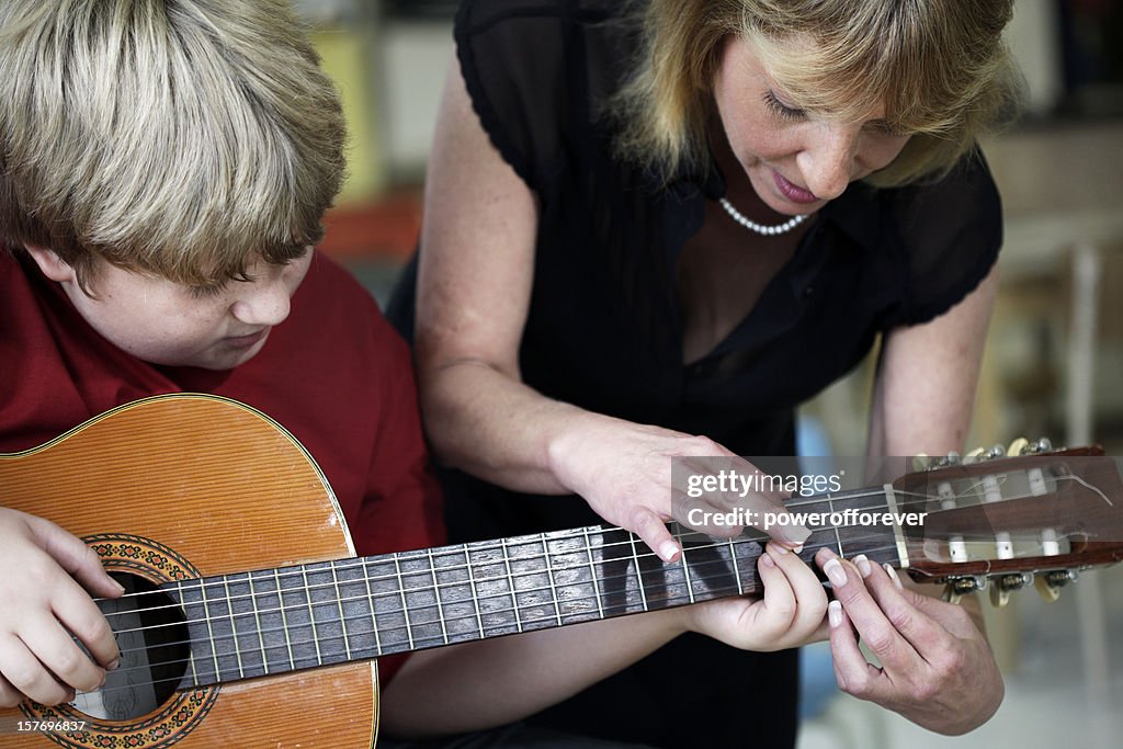 Boy Learning to Play Guitar in Music Class