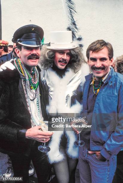 Portrait of three unidentified men, two in costume and two with martini glasses, as they pose together during Mardi Gras on Bourbon Street, New...