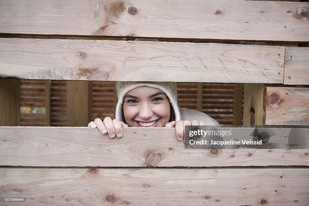 Woman peeking out of wooden structure