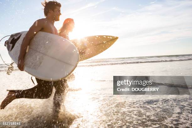 surfers at the beach - surfers in the sea at sunset stock pictures, royalty-free photos & images