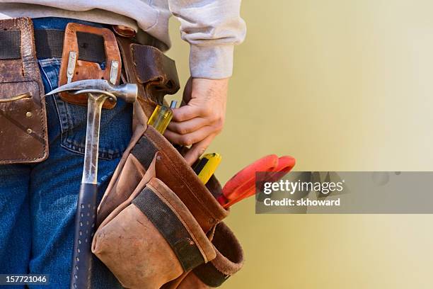 joven trabajador de construcción alcanza en este cinturón de herramientas se fabrica con espacio de copia - martillo herramienta de mano fotografías e imágenes de stock