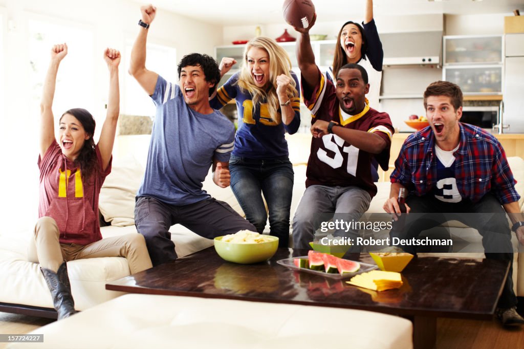 Friends watching football in living room.