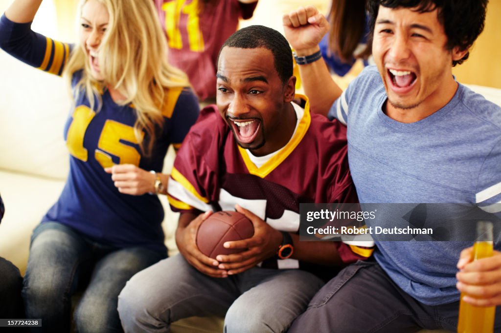 Friends watching football in living room.