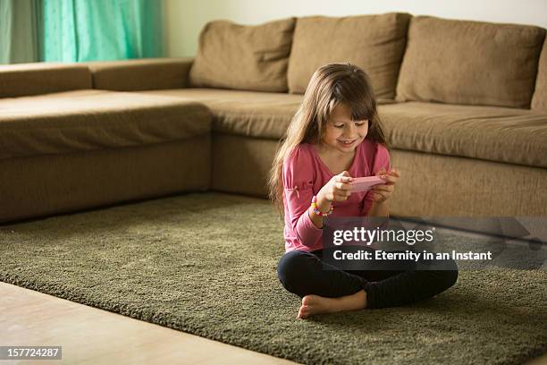 young girl playing with smartphone in living room - sitting on floor stock pictures, royalty-free photos & images