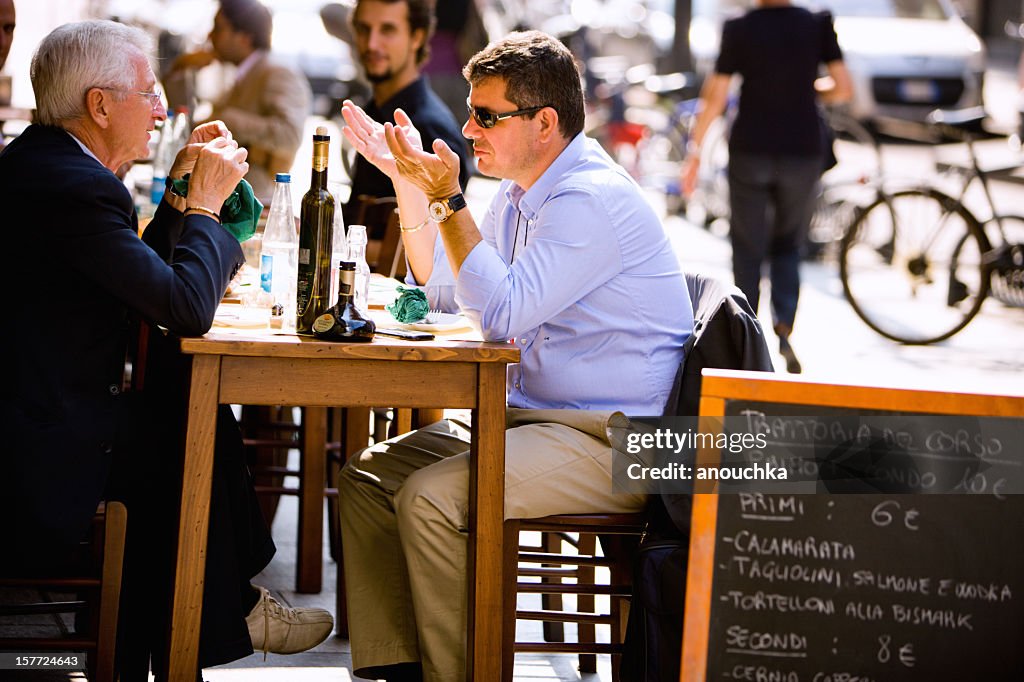 Two men having lunch in outdoor cafe, Milan, Italy