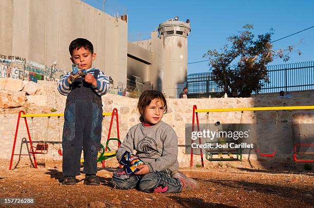 palestinian children at playground beside separation barrier wall in bethlehem - palestinian boy stock pictures, royalty-free photos & images