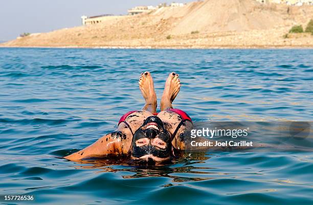 mar morto vacanza con donna galleggianti sul dietro - dead sea foto e immagini stock