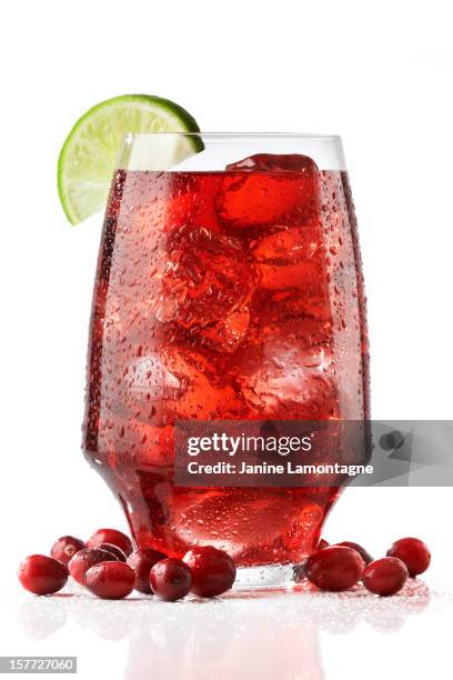 a wide tall glass of fresh cranberry juices served with lime - veenbessensap stockfoto's en -beelden