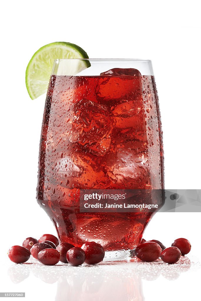 A wide tall glass of fresh cranberry juices served with lime