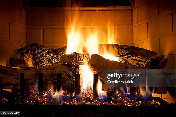 burning logs and glowing embers in gas fireplace - haardvuur stockfoto's en -beelden