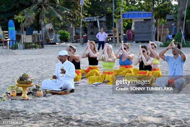 Foreign tourists participate in a Balinese Hindu prayer gathering on a beach in Seminyak near Denpasar on Indonesia's resort island of Bali on August...