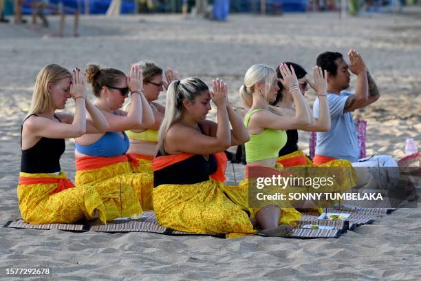Foreign tourists participate in a Balinese Hindu prayer gathering on a beach in Seminyak near Denpasar on Indonesia's resort island of Bali on August...
