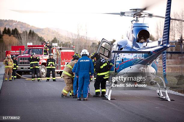 feuerwehrleute laden ein gurney warten hubschrauber - rettungshubschrauber stock-fotos und bilder