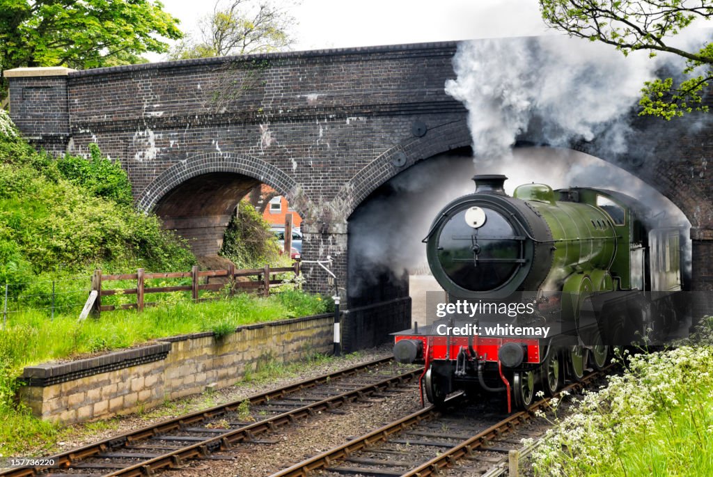 Steam train passing under a bridge