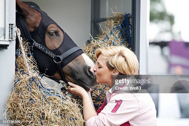 attractive woman kissing a horse - horse trailer stock pictures, royalty-free photos & images