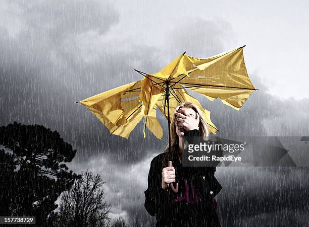 thunderstorm gets the better of umbrella and woman holding it - broken umbrella stockfoto's en -beelden
