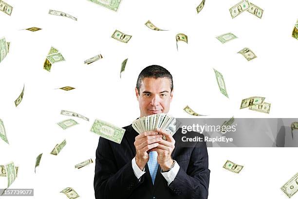 happy businessman with fistful of dollars plus more raining down - raining money stockfoto's en -beelden