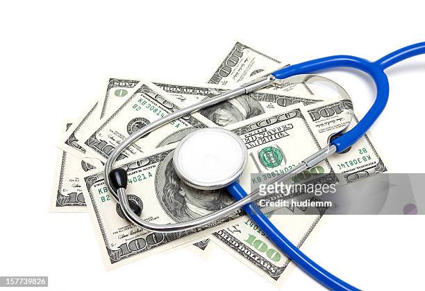 stethoscope on us dollars isolated on white background - medicaid stock pictures, royalty-free photos & images