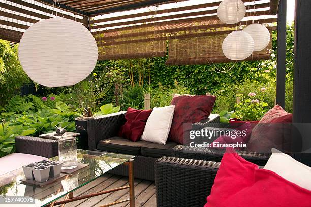 a garden patio with wicker sofas surrounded by trees - garden furniture stockfoto's en -beelden