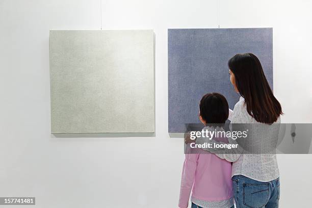 mother and daughter looking at painting in an art gallery - arts related stock pictures, royalty-free photos & images
