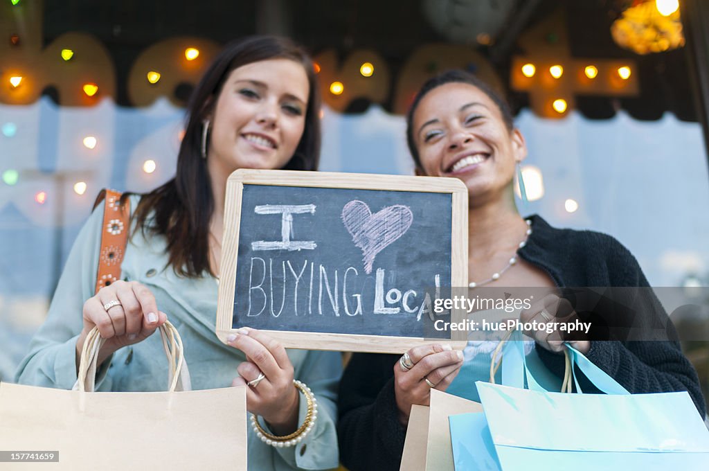 Two women holding up sign for buying local