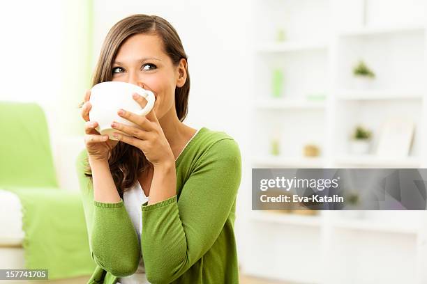 beautiful woman enjoying a cup of coffee at home - woman drinking tea stockfoto's en -beelden