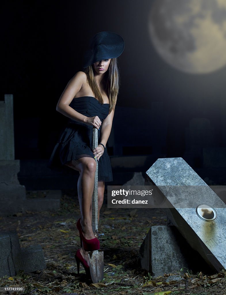 Mulher no preto com showel em graveyard