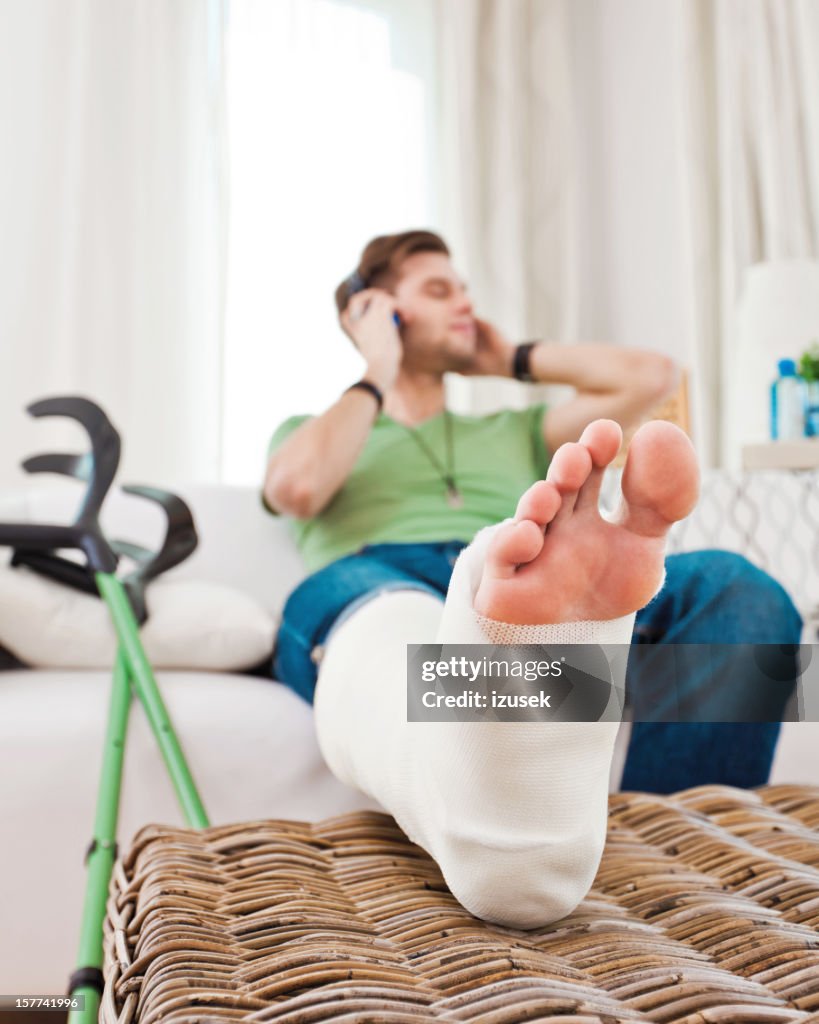 Young man with broken leg at home