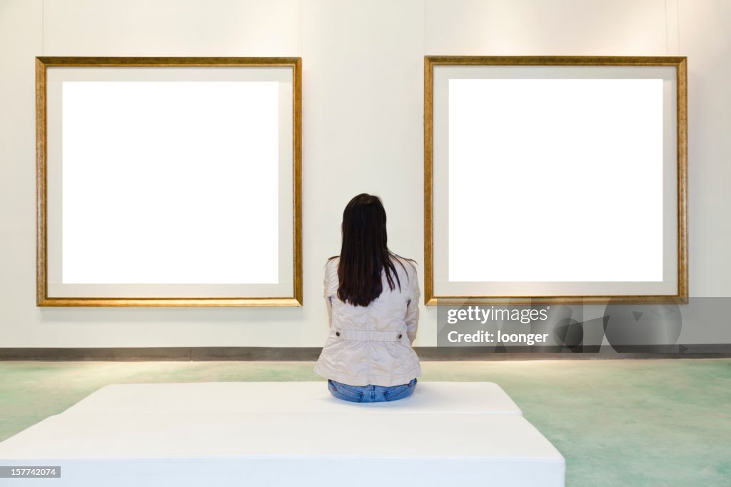 One woman looking at white frame in an art gallery