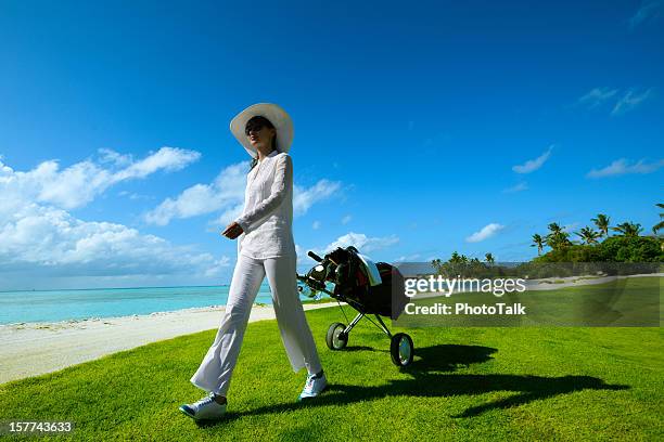 female golfer with cart walking on beach golf course - big island hawaii islands stock pictures, royalty-free photos & images