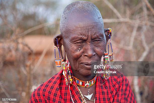 old maasai woman with traditional jewellery in front of hut - scarification stock pictures, royalty-free photos & images