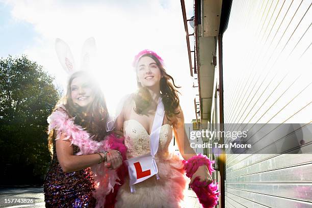 two women dressed for hens party running on street - addio al nubilato foto e immagini stock