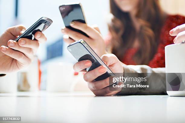 hands texting with mobile phones in cafe - drahtlose technologie stock-fotos und bilder