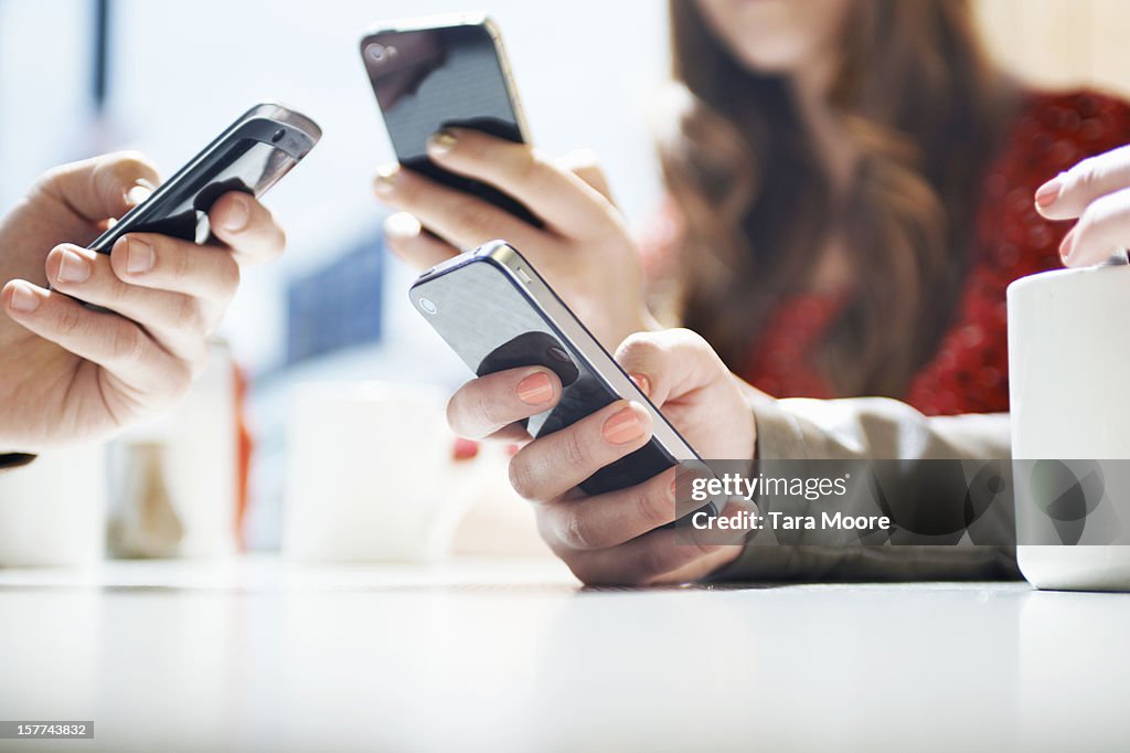 Hands texting with mobile phones in cafe