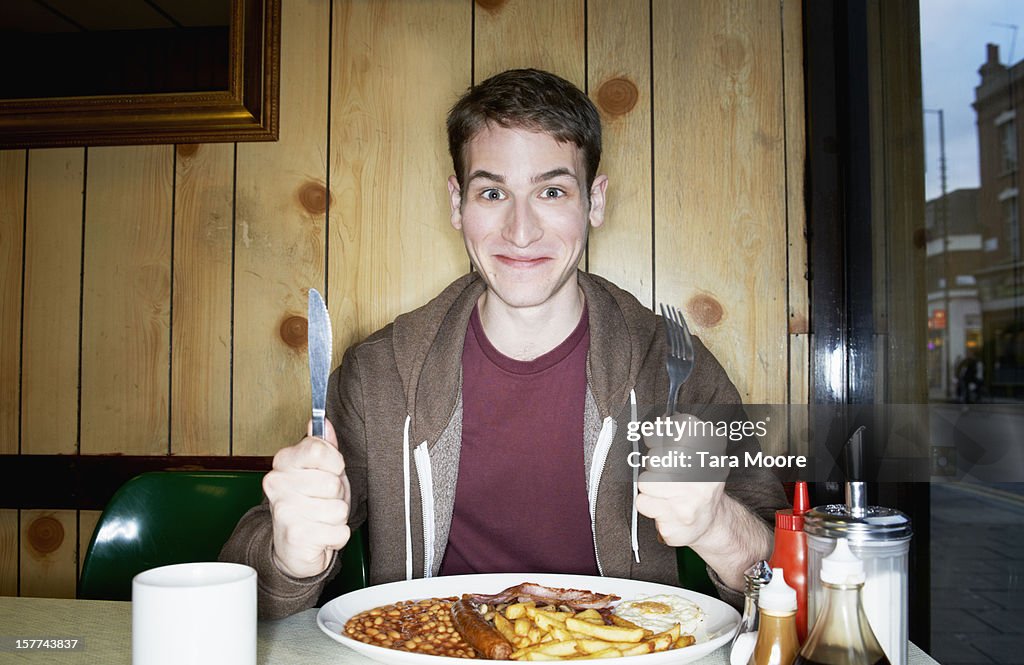 Young man with big breakfast in cafe