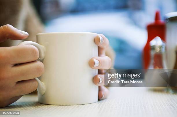 close up of hands holding cup of coffee in cafe - mug photos et images de collection