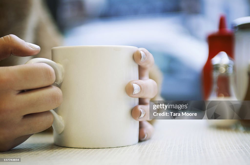 Close up of hands holding cup of coffee in cafe