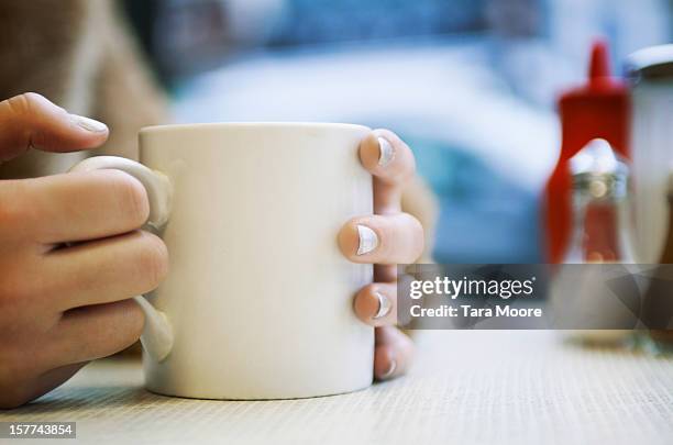 close up of hands holding cup of coffee in cafe - マグカップ ストックフォトと画像