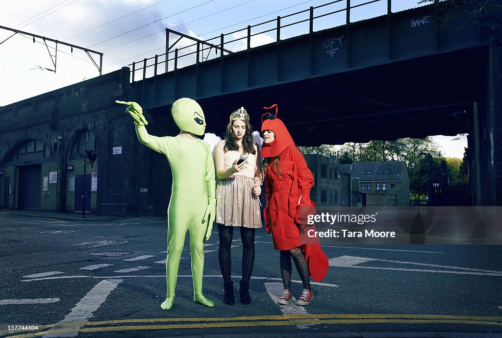 Friends in fancy dress checking mobile for map