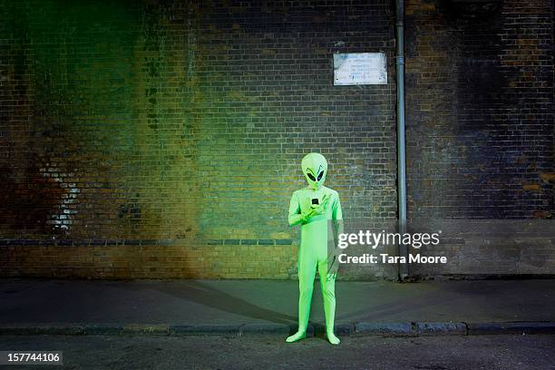 man dressed in alien costume looking at mobile - außerirdischer stock-fotos und bilder